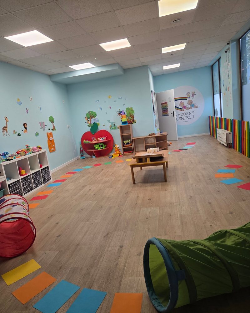 Duża sala zabaw z tęczowym płotkiem i zabawkami