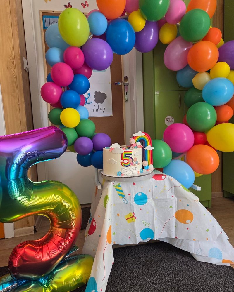 Tęczowa brama z balonów i tort na urodziny żłobka