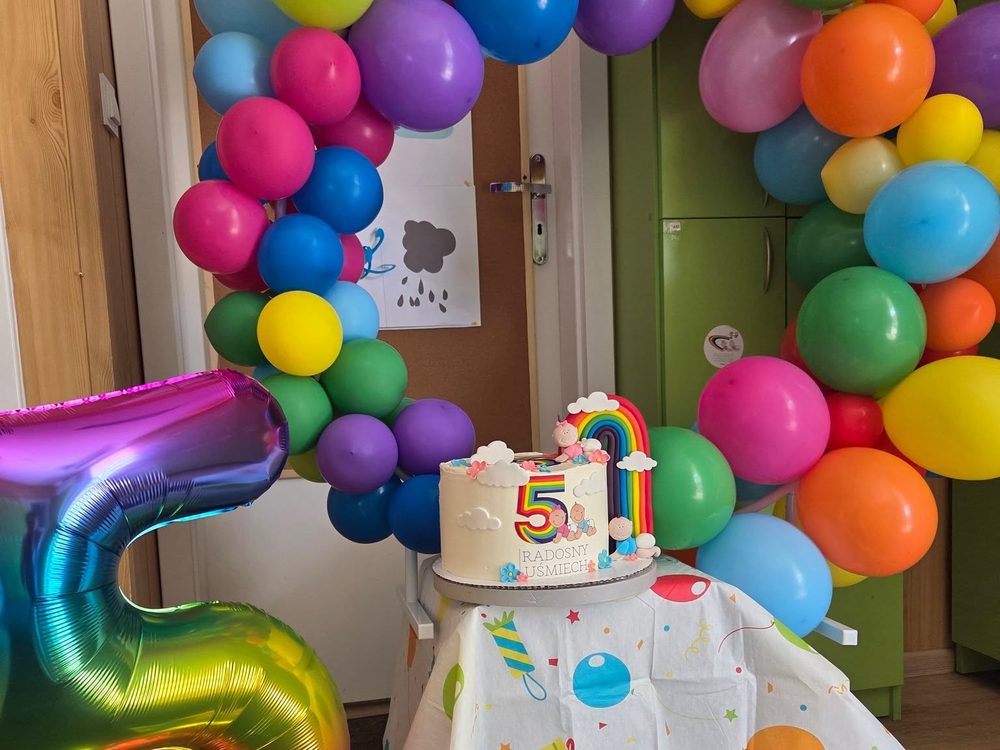 Tęczowa brama z balonów i tort urodzinowy w żłobku Radosny Uśmiech